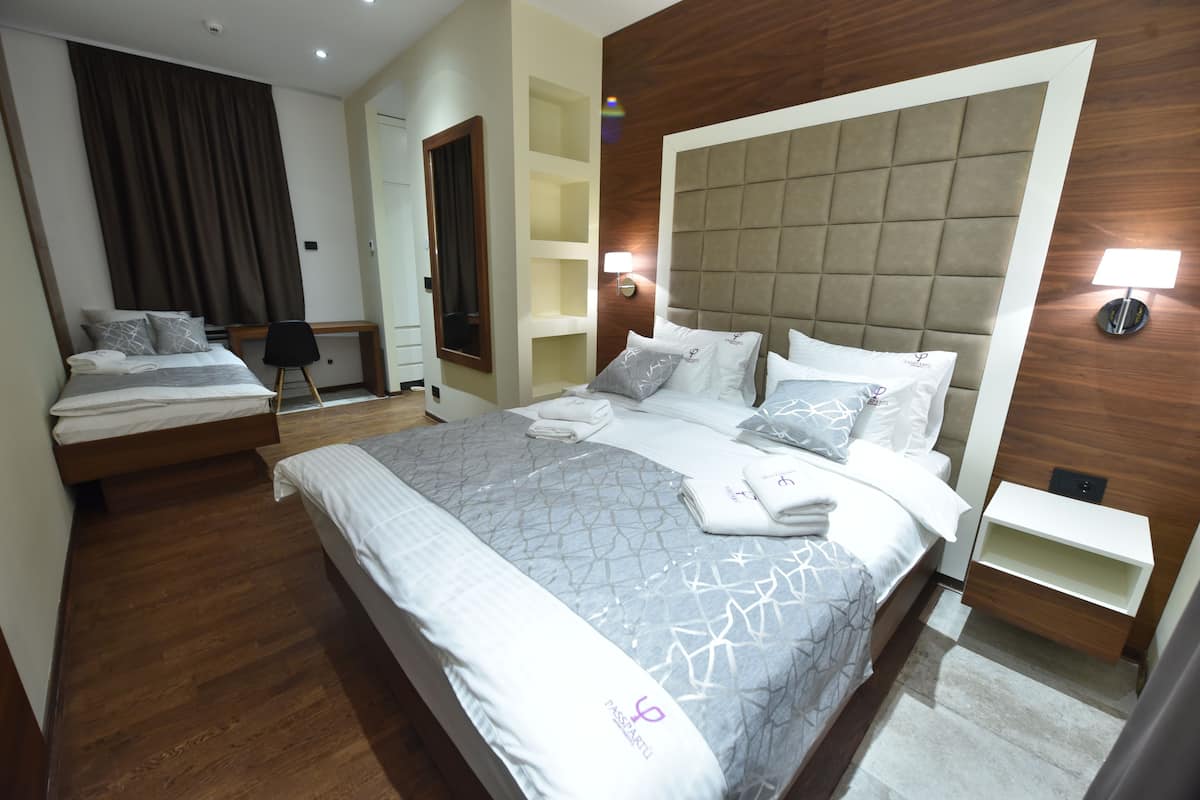 A hotel room with a large bed, a smaller bed, a desk, and a wardrobe.