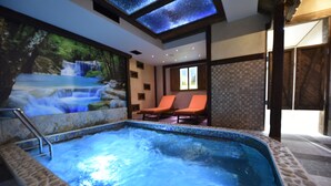 A hot tub with a waterfall mural, two lounge chairs, and a tiled wall. - Passpartù (Belgrade)