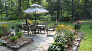 A patio with stone flooring, a table with chairs, and an umbrella.