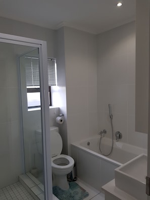 A modern bathroom with a toilet, shower, and glass-enclosed shower stall. - Nova Luxury Suites Saratoga 112 (Sandton)