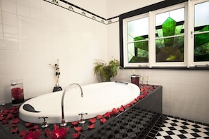 A bathroom with a white bathtub, black checkered floor, and a window with green glass panes. - The Gatsby (Katoomba)