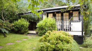 Una casa moderna con porche cubierto, rodeada de exuberante vegetación y un jardín bien cuidado.