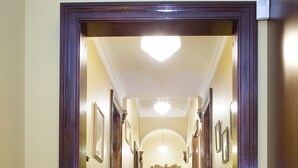 Um corredor com carpete estampado, portas de madeira e escada que leva a um andar superior.