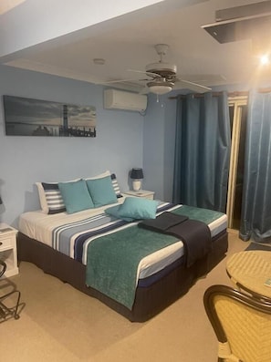 A bedroom with a bed, nightstands, a chair, a ceiling fan, and a window with curtains. - Tambaridge Bed and Breakfast (Wongawallan)