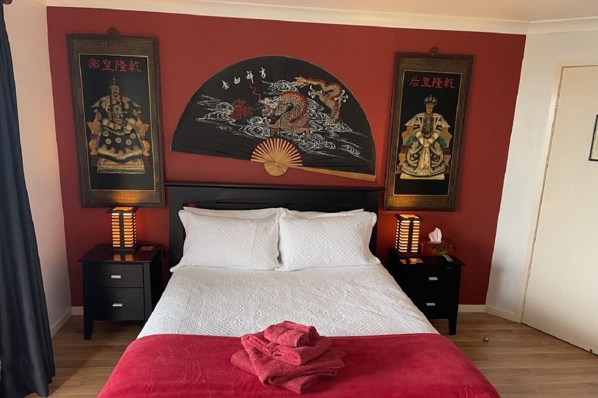 A hotel room with a bed, two nightstands, and two wall-mounted lamps.