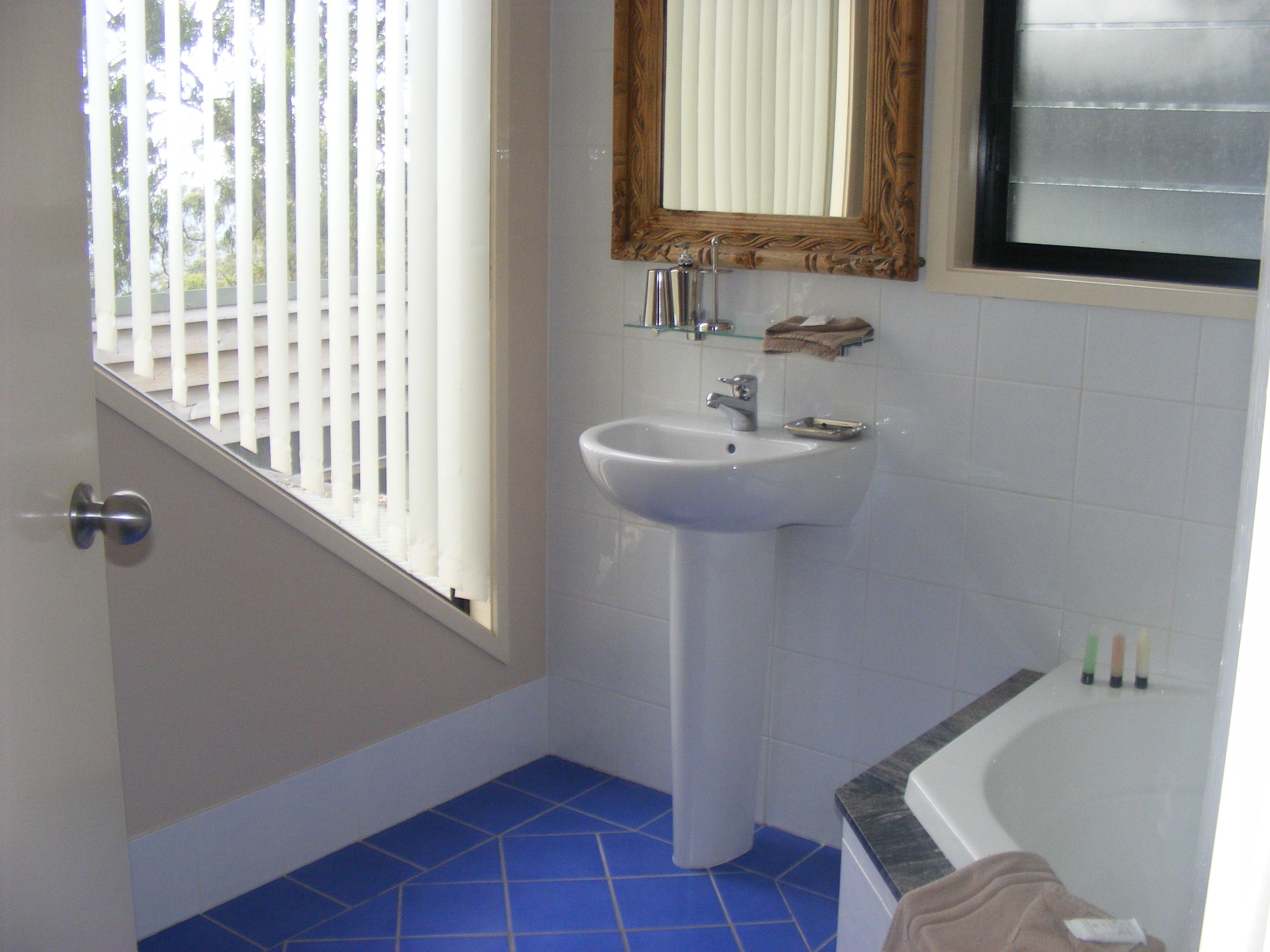 Un baño con lavamanos blanco, espejo y bañera.