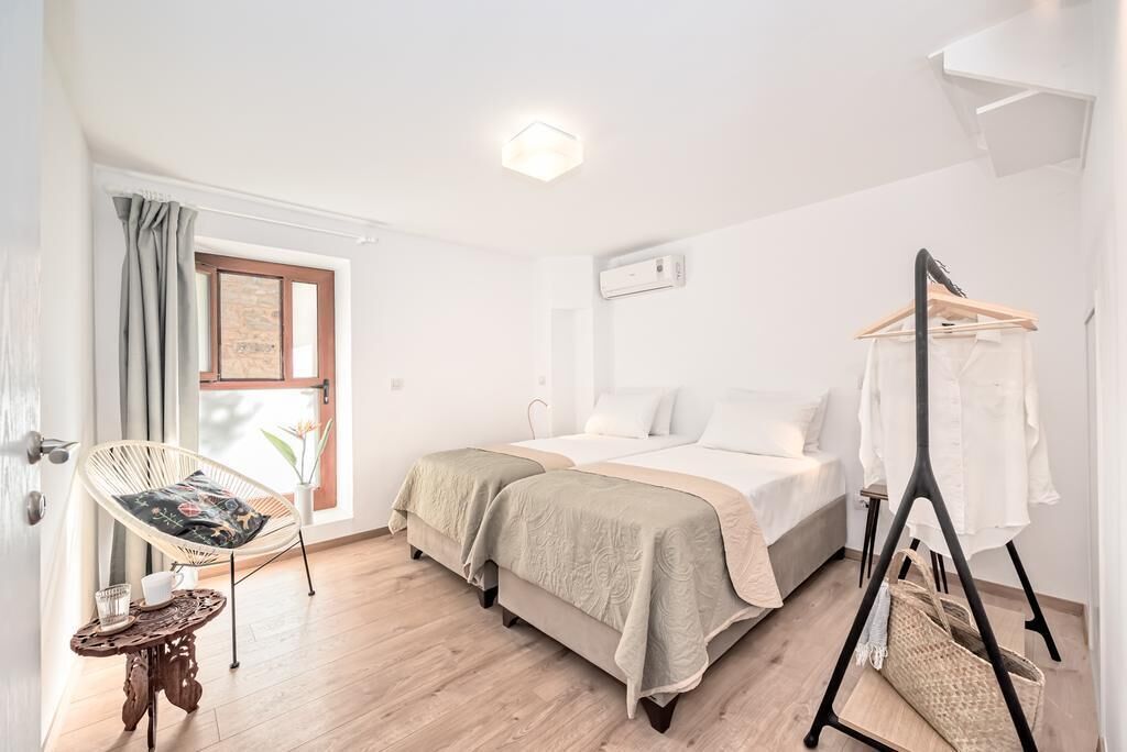 A bedroom with a bed, a chair, a table, and a clothing rack.
