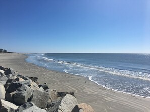 En strand med en stenig kustlinje och vågor som försiktigt sköljer in mot sanden.