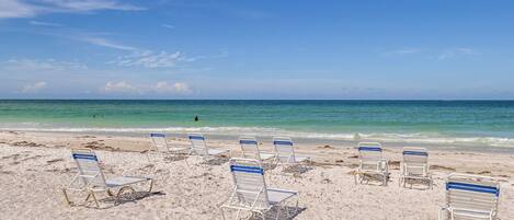 A beach with rows of empty beach chairs and a clear view of the ocean.