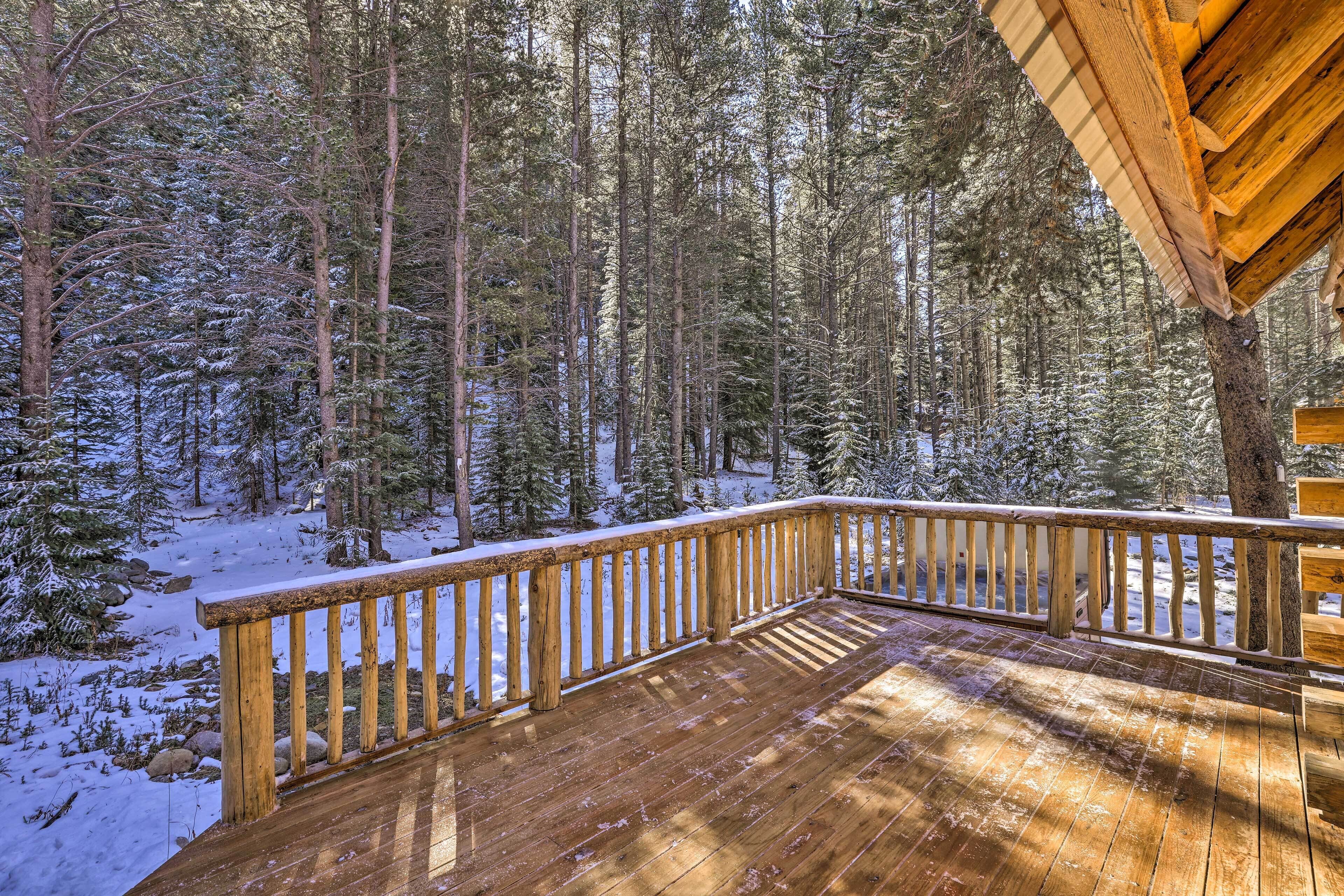 A wooden deck with a railing overlooking a snowy forest.