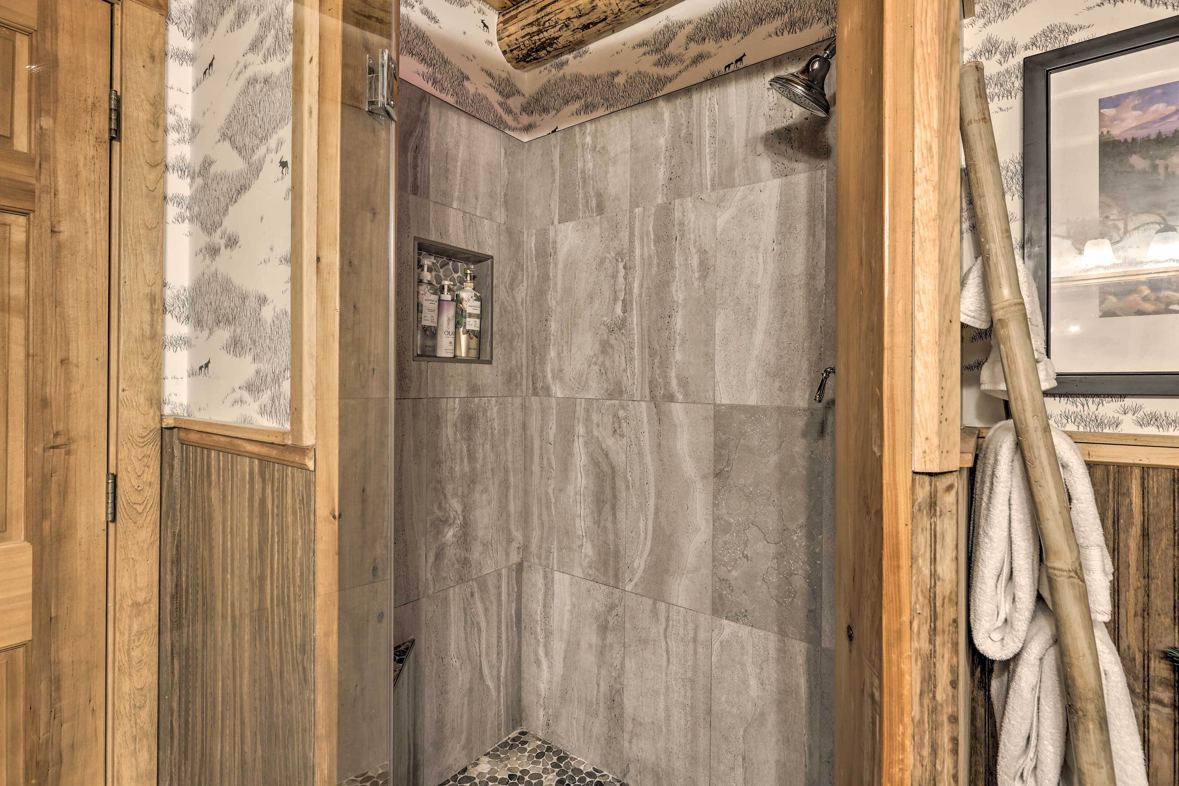 Een douche met een houten deur, een handdoekhouder en een lijst met een foto aan de muur.