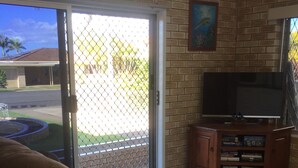 A living room with a brown couch, a TV on a wooden stand, and a bookshelf. - Holiday at Hillcrest (Scarness)