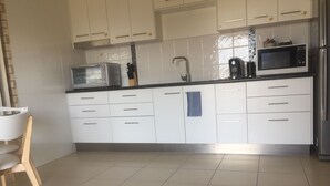 A modern kitchen with white cabinets, a microwave, a kettle, and a sink. - Holiday at Hillcrest (Scarness)