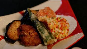 A plate with various dishes including fried items, a rolled vegetable, and a rice-based dish.
