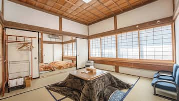 A traditional Japanese room with tatami flooring, a low table, a sofa, and sliding doors.