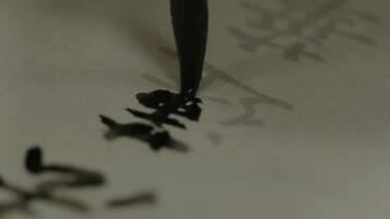 A close-up of a pen tip with ink on a surface.