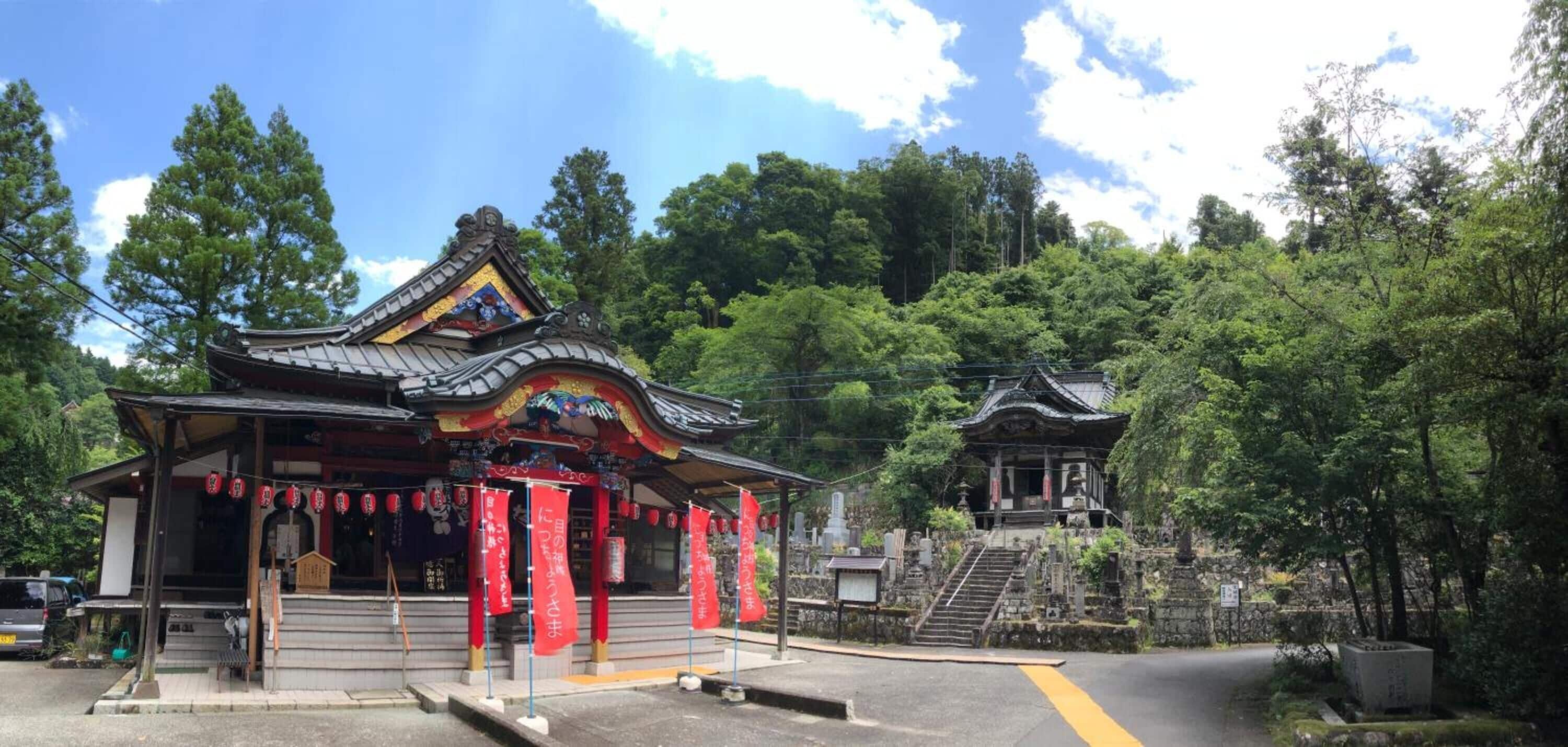 A traditional Japanese temple with a sloped roof, a small shrine, and a stone staircase leading up to it.