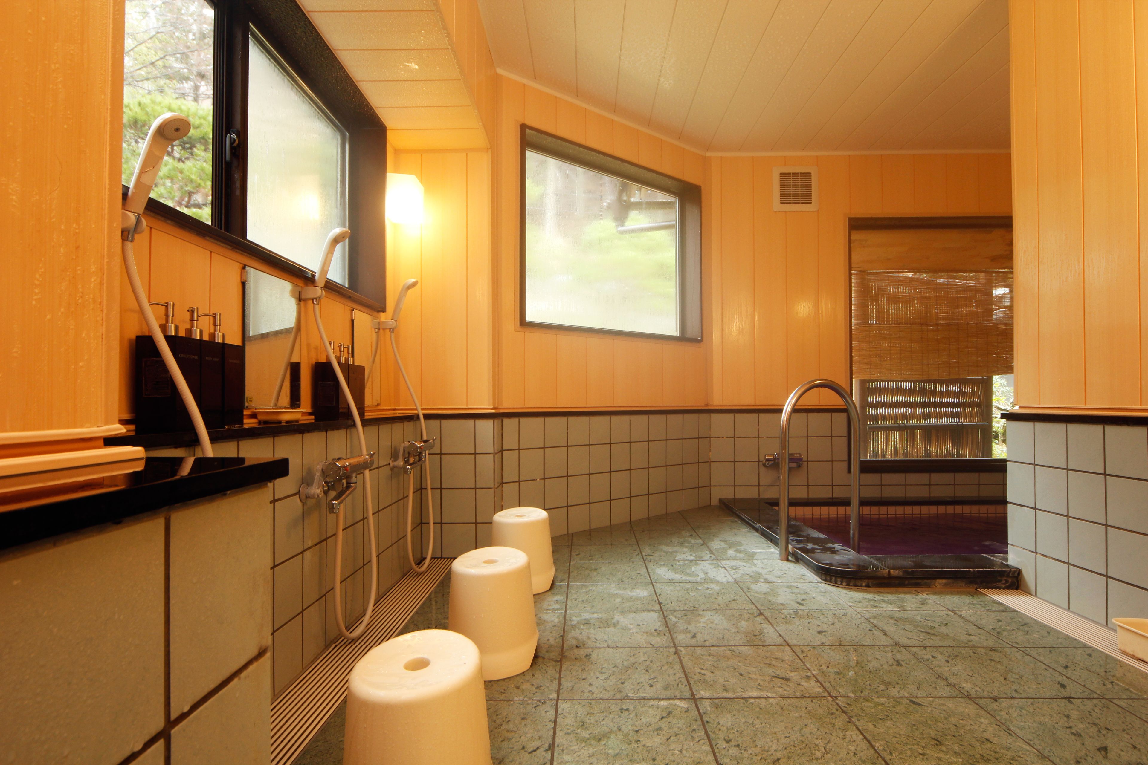 A bathroom with a shower, toilet paper, and a window.