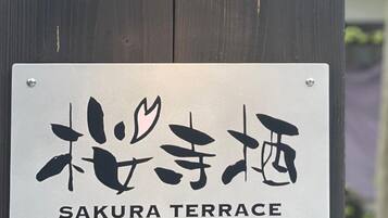 Señal para la Terraza Sakura, con caracteres japoneses y texto en inglés que invita a disfrutar de la terraza.