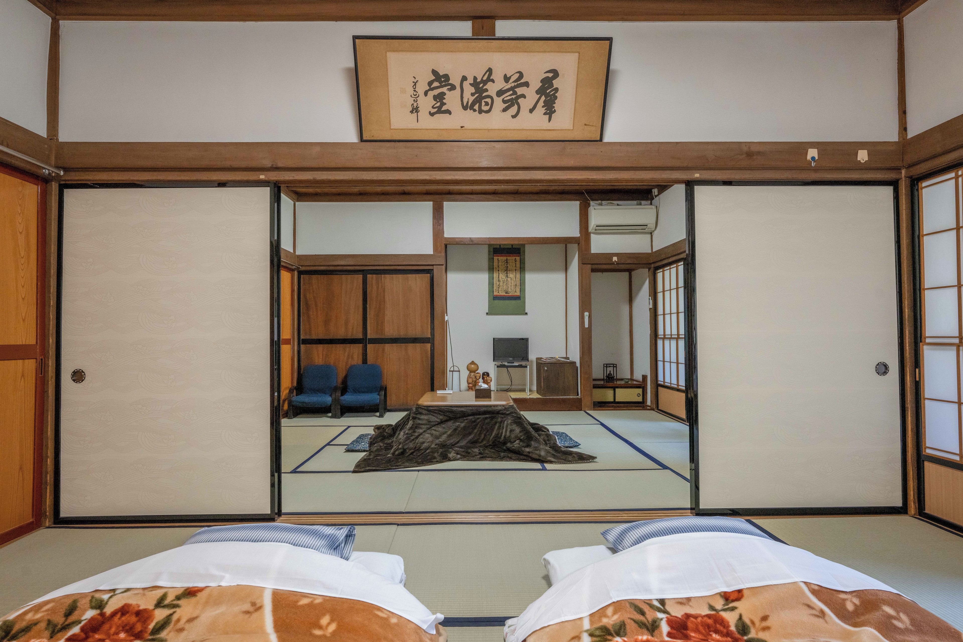 A traditional Japanese room with tatami flooring, a low table, and a sliding door.