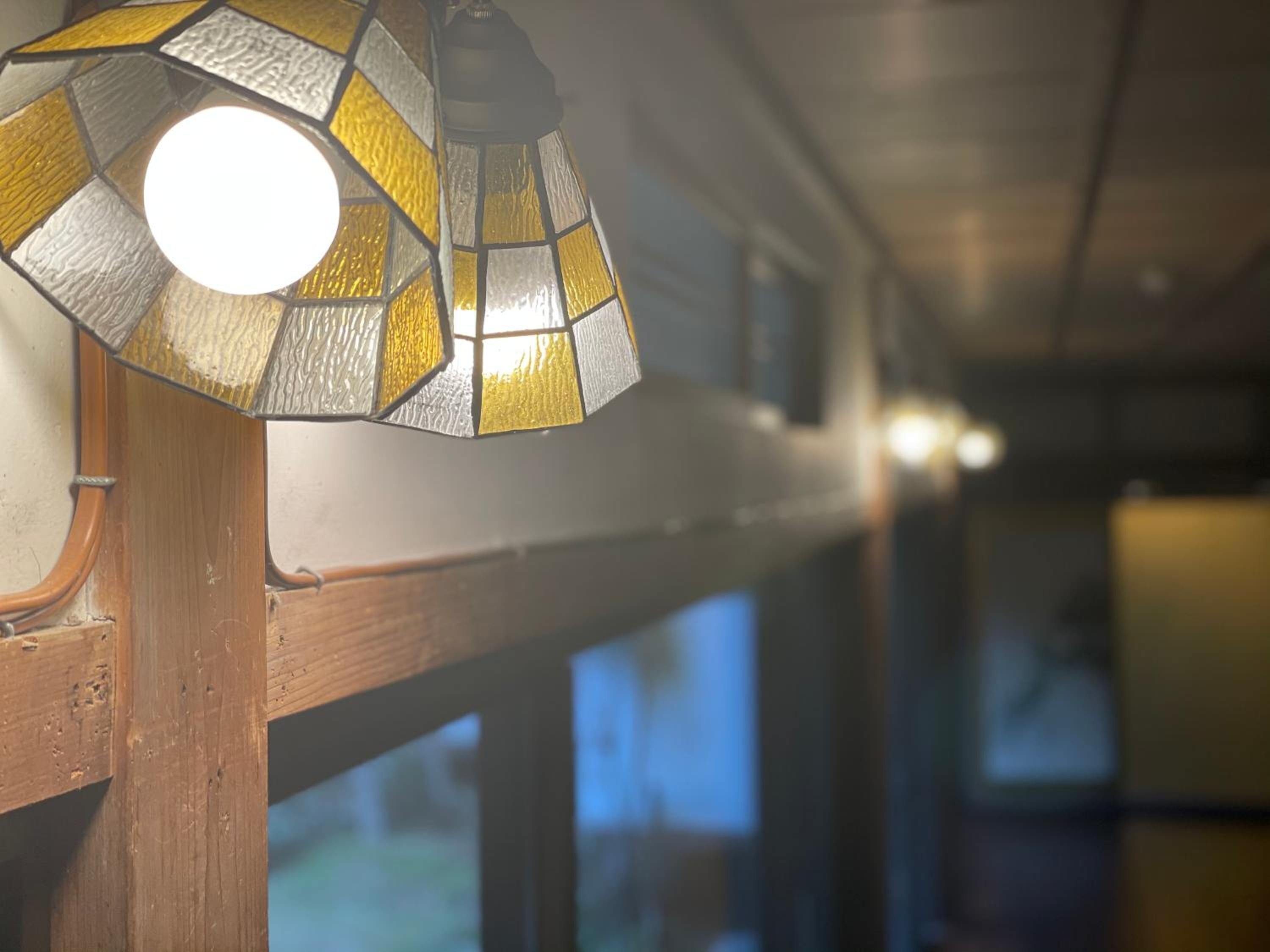 A close-up of a stained glass light fixture with a round bulb, mounted on a wooden structure.