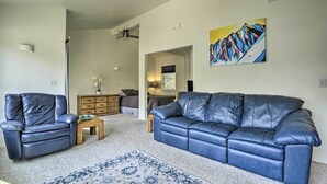 A living room with a blue leather sofa, a matching armchair, a wooden coffee table, and a patterned rug. - Cabin w/ Hot Tub & Views: 1 Mile to Alyeska Resort (Girdwood)