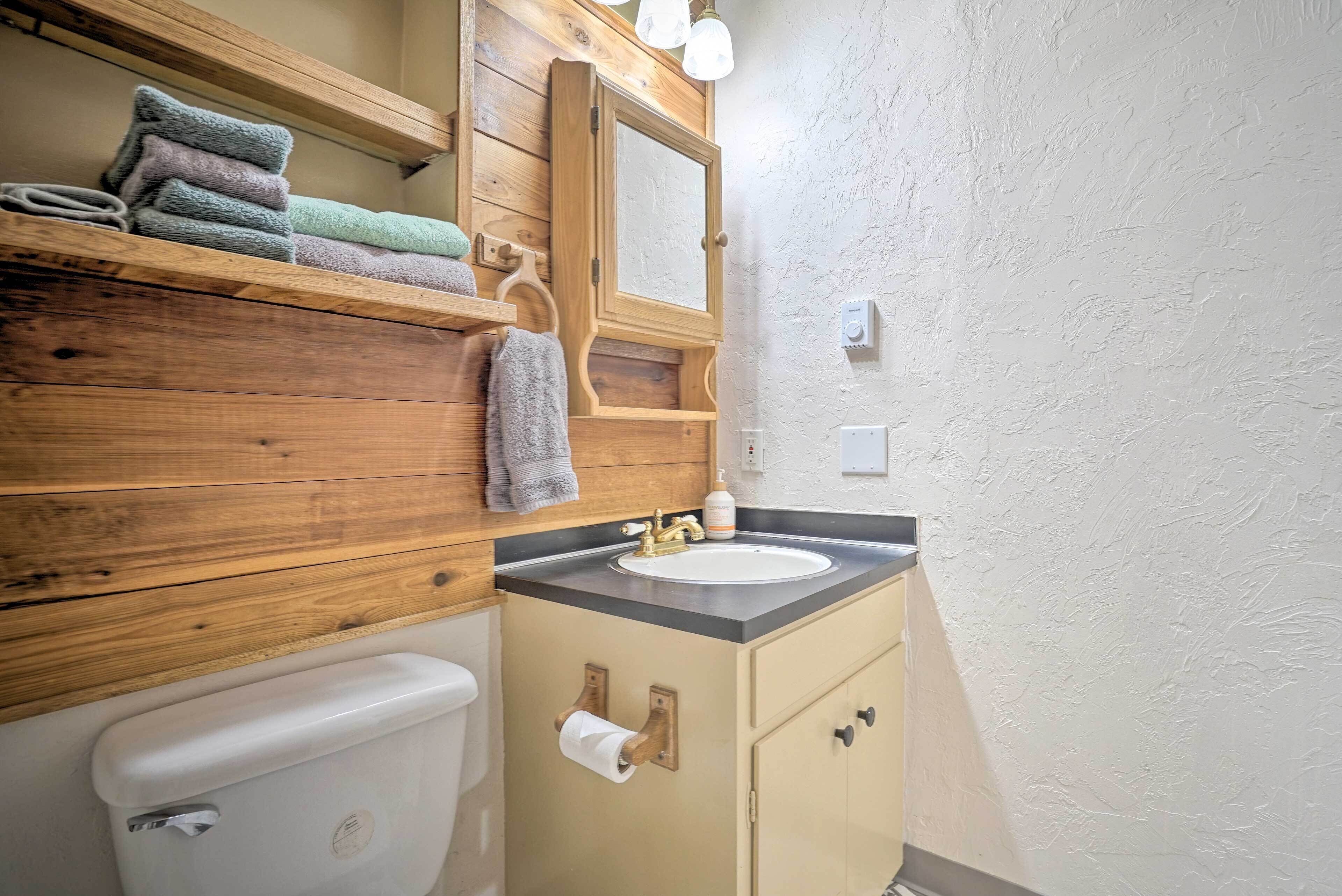 Un baño con tocador de madera, lavamanos y retrete.