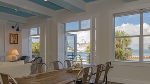 A dining area with a wooden table and metal chairs, a glass jar with decorative items, and a view of a cruise ship through large windows. - A Sunset & Harbour View at The Truman Annex in Key West (Key West)