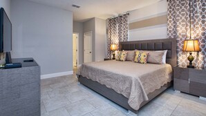 A bedroom with a large bed, two bedside lamps, a nightstand, and a TV on a stand. - Affordable and so close to Disney  Solterra Resort (Davenport)
