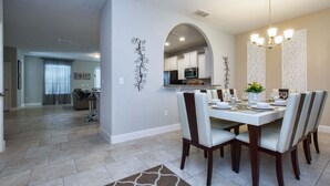 A dining area with a white table set for four, surrounded by chairs. - Affordable and so close to Disney  Solterra Resort (Davenport)