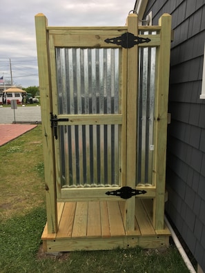 Un portón de madera con una reja de metal, una puerta de madera y un escalón que lleva a ella.
