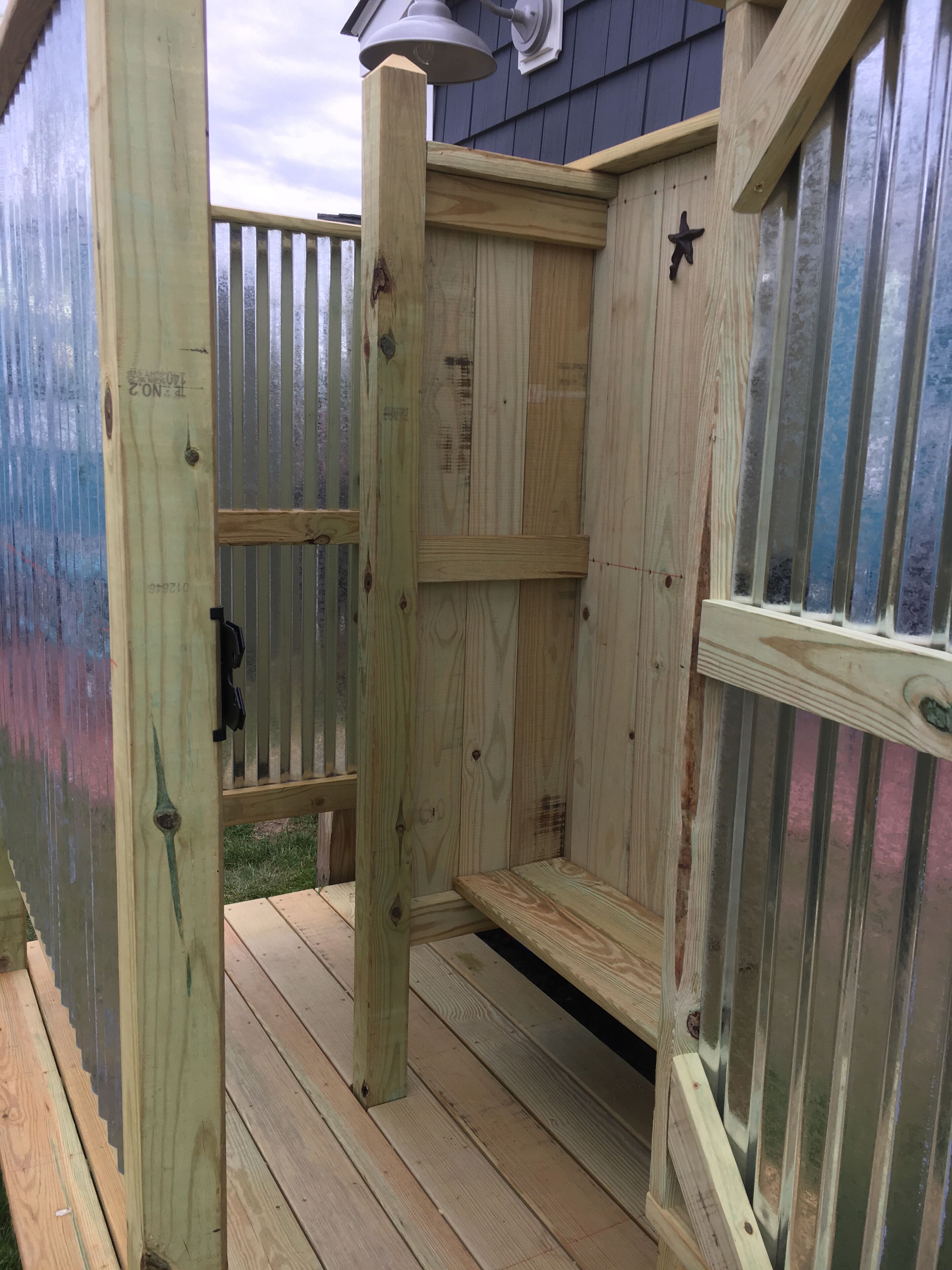 A wooden deck with a metal railing, a wooden bench, and a window with a star decoration.