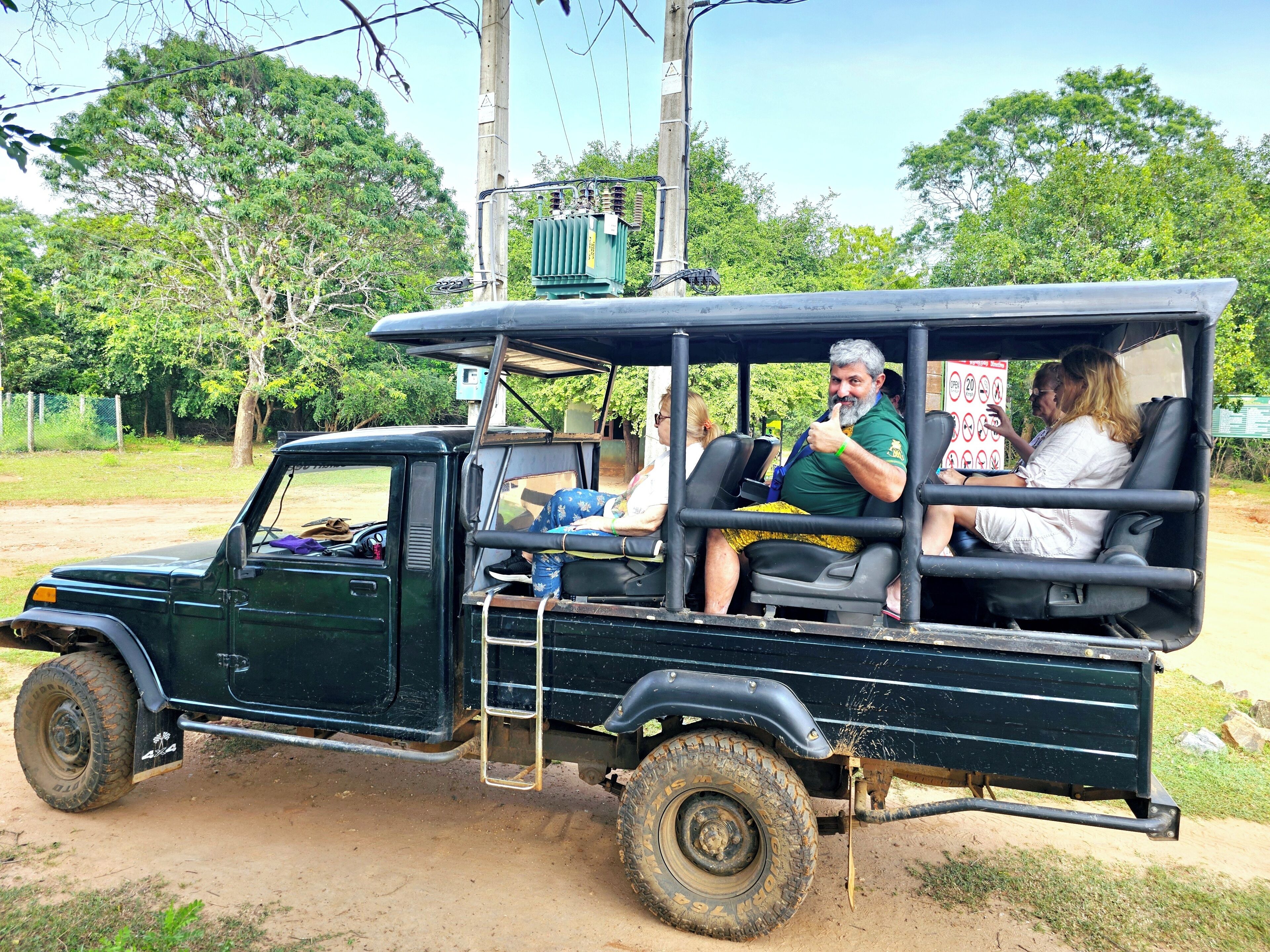 Un jeep verde con pasajeros, una escalera y un cartel en la parte trasera.