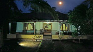 Une maison à deux étages avec un porche, un coin repas et une chambre visible de l’extérieur.