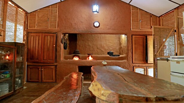 Une cuisine rustique avec des meubles en bois, un poêle central et un ventilateur de plafond.