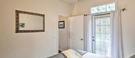 A bedroom with a bed, a ceiling fan, a window with blinds, and a door.