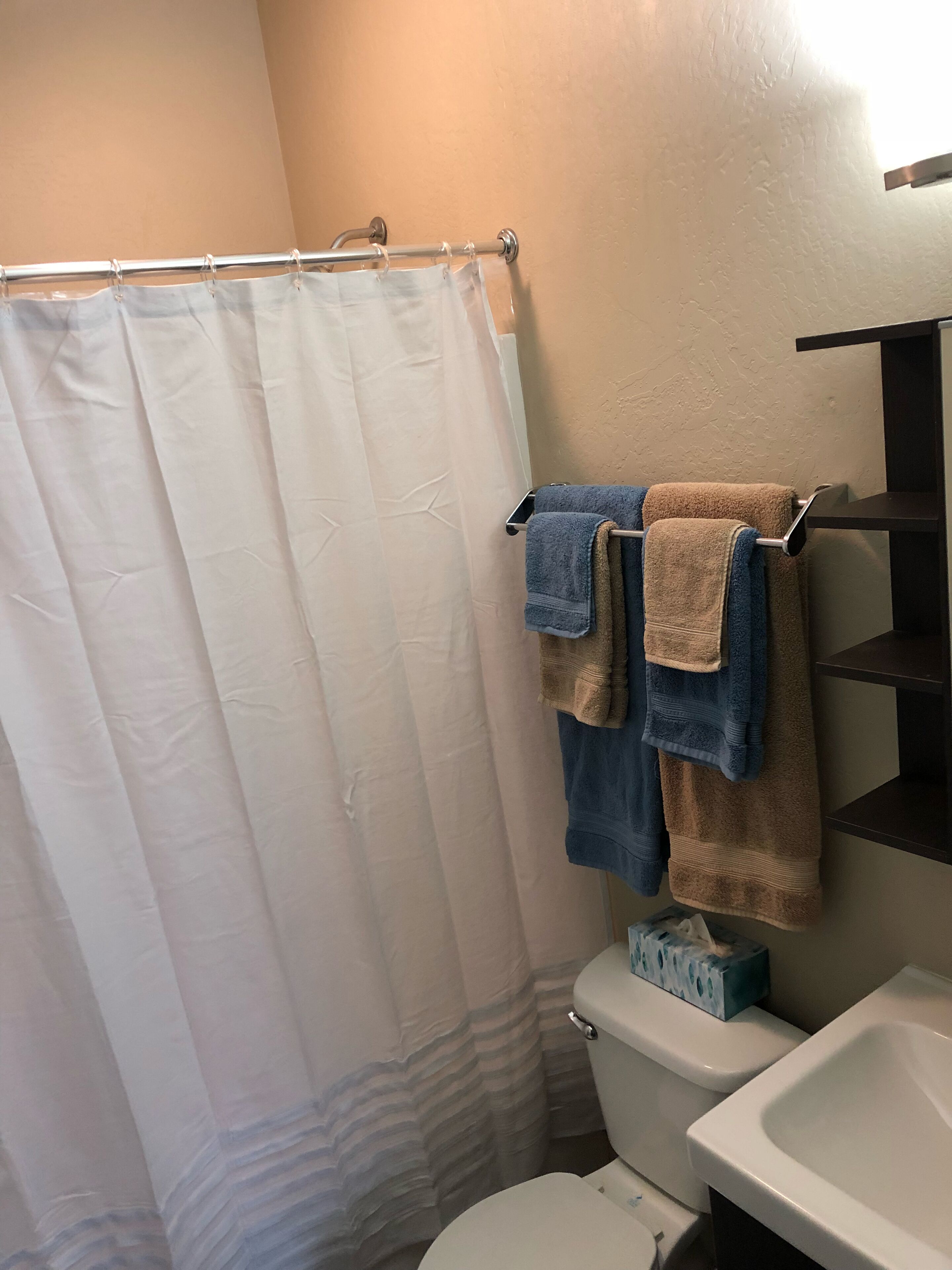 Een bad/douchecombinatie, een haardroger, handdoeken, zeep