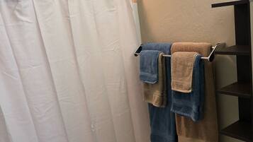 Een bad/douchecombinatie, een haardroger, handdoeken, zeep