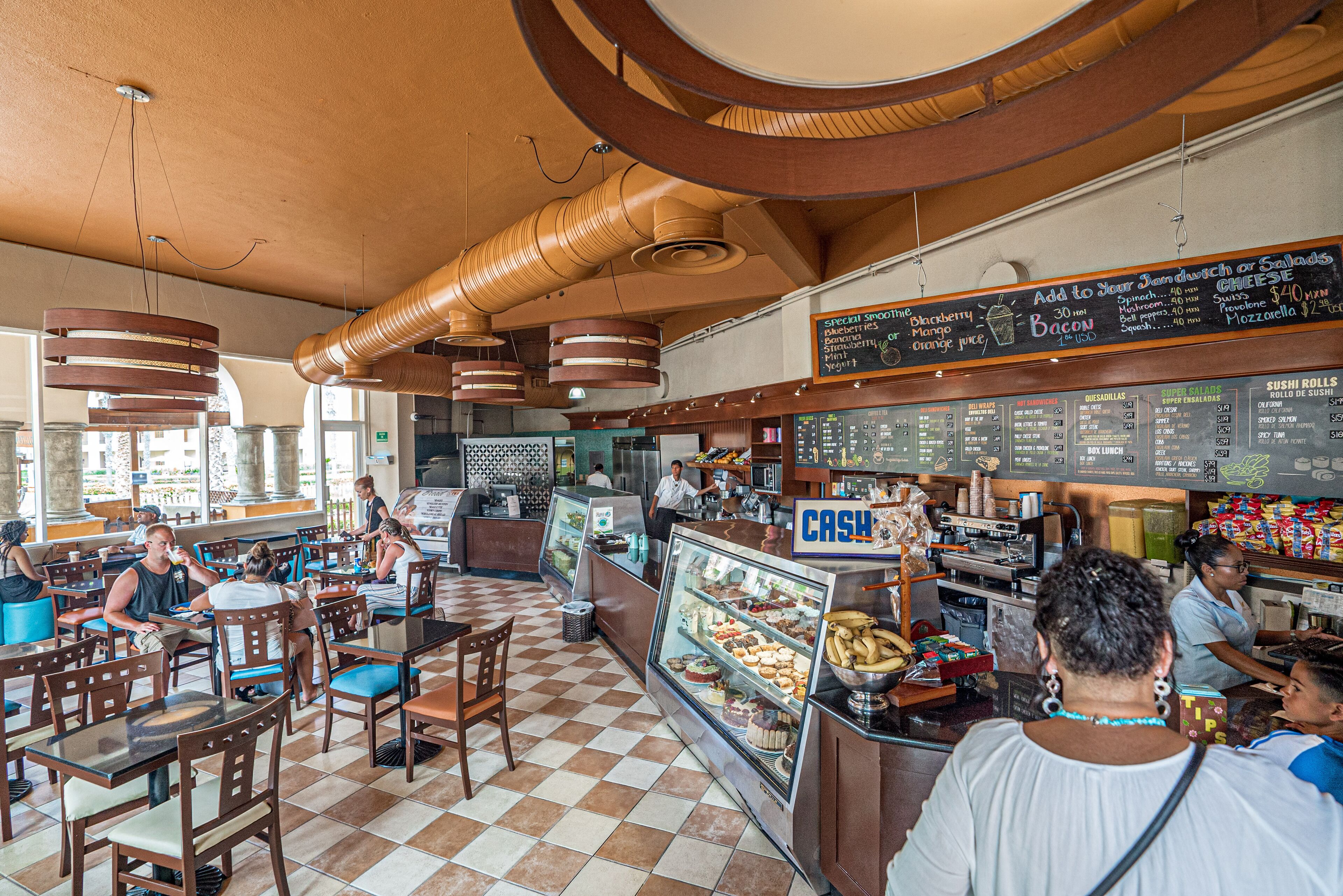 A restaurant interior with checkered flooring, wooden furniture, a cash register, and a menu board.