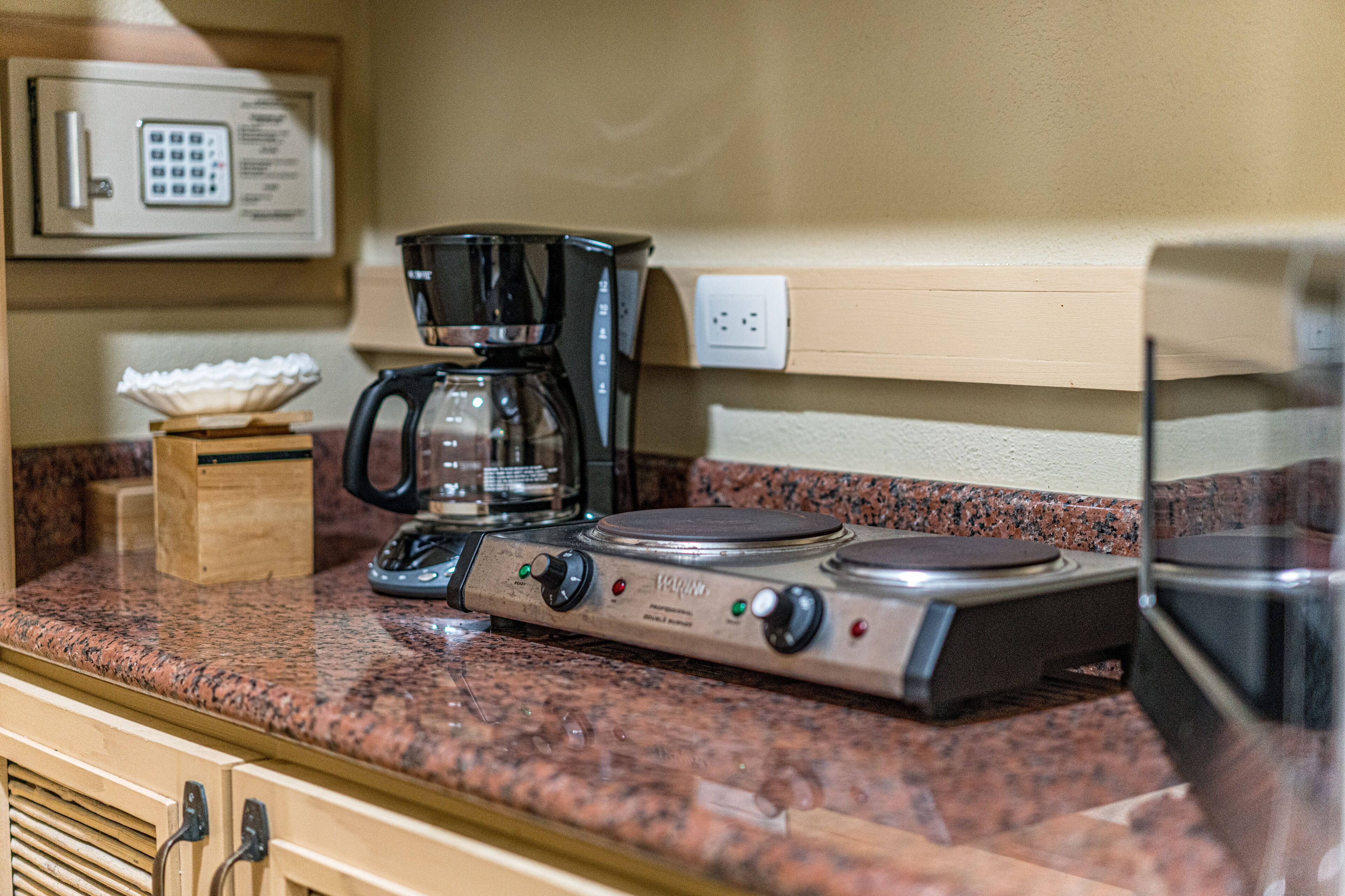 A kitchen with a stove, coffee maker, and microwave.