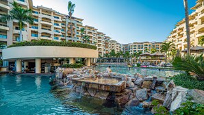 Et resort med en stor pool omgivet af klippeformationer og palmer.