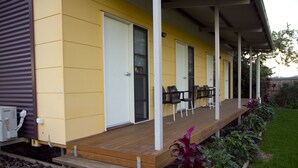 A yellow building with a covered porch, wooden benches, and chairs. - The Three Ways Alligator Creek (Alligator Creek)
