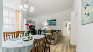 A dining area with a table set for four, a sofa, and a television in the background.