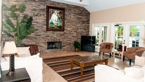A living room with a stone fireplace, a television, and comfortable seating.