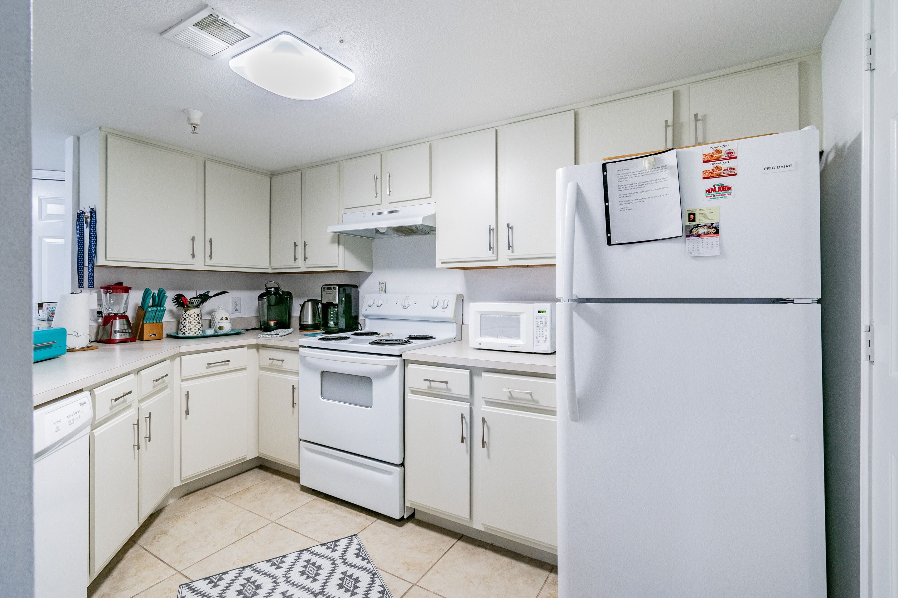A kitchen with white cabinets, a stove, a microwave, and a refrigerator.