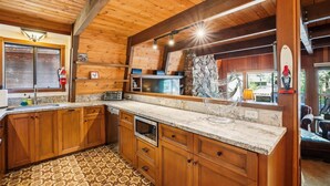 Una cocina de estilo cabaña de madera, con protector de piedra, armarios de madera y encimera de granito.