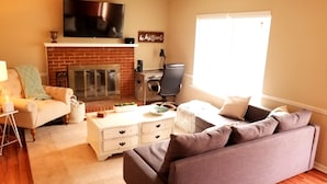 Una sala de estar con chimenea, televisor, sofá y mesa de centro.