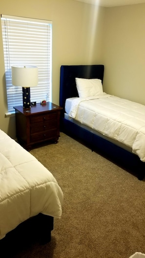 A bedroom with two beds, a nightstand, a lamp, and a clock.