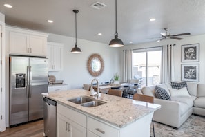 Enjoy cooking in the well-equipped kitchen with a central island, sink, and dishwasher, and dine in the adjacent dining area with a casual table and chairs.