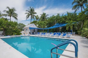 A swimming pool with blue lounge chairs and a small building in the background.